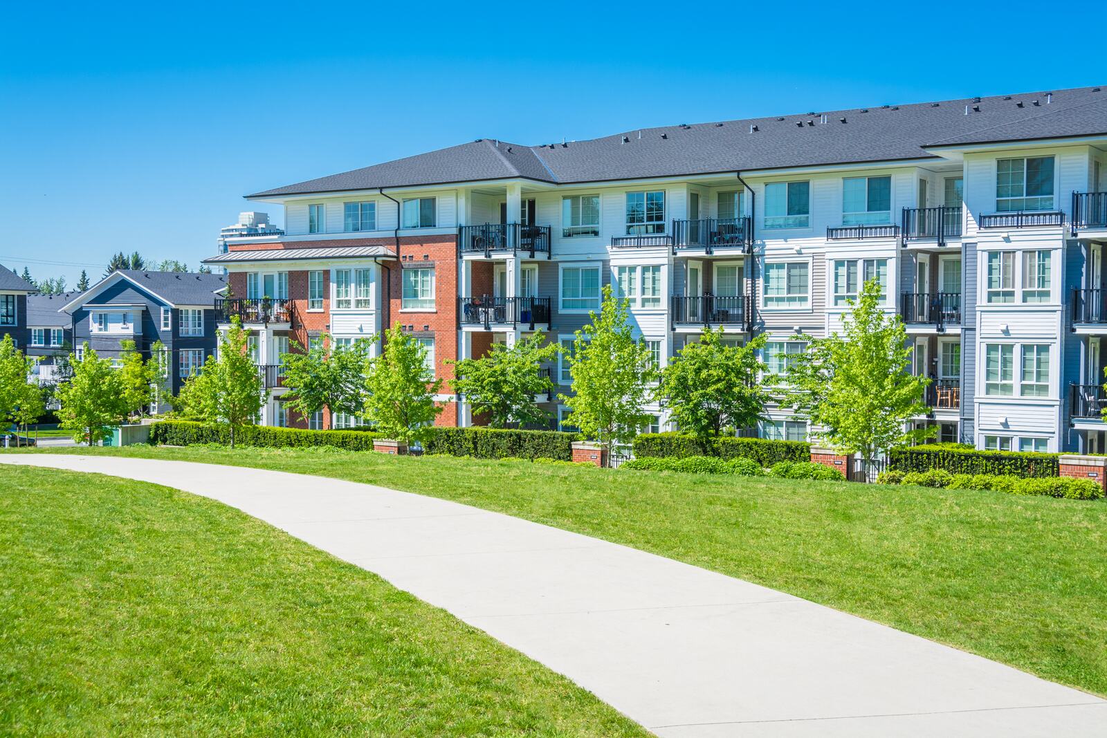 Curved concrete walkway between brick townhomes at a multifamily community
